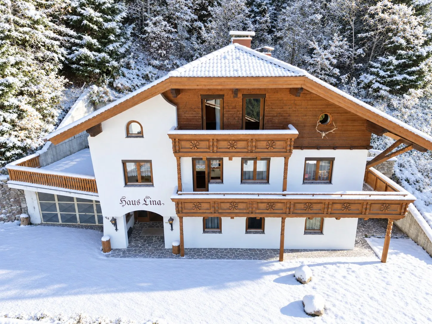 Haus Lina in the snow, with its balconies and carved wooden railings